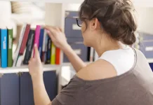 Woman choosing favourite book from home library